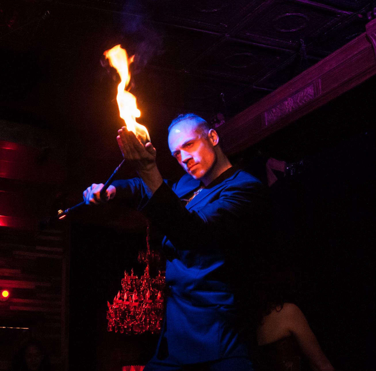 John performing with a flame in dramatic blue and burgundy lighting