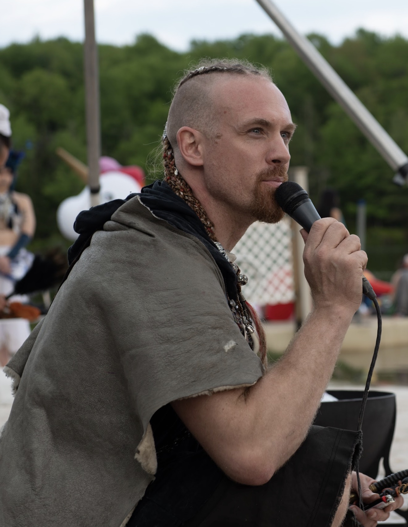 John speaking into a microphone at an outdoor event